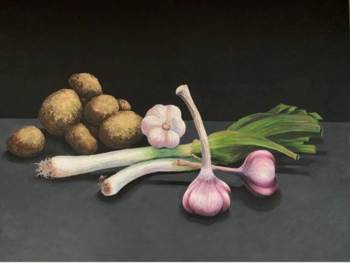 Hintergrund schwarz, darauf frische Knoblauchzehen und Frühlingszwiebeln neben Kartoffeln.