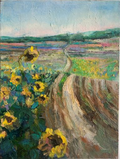 Landschaft mit Sonnenblumen Sonnenblumen im Vordergrund, hintergründige Felder und ein Weg unter blauem Himmel.