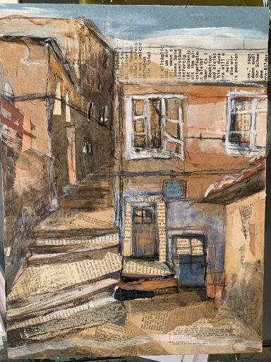 Gassenansicht mit Treppe und Häusern in warmen Erdtönen unter blauem Himmel.